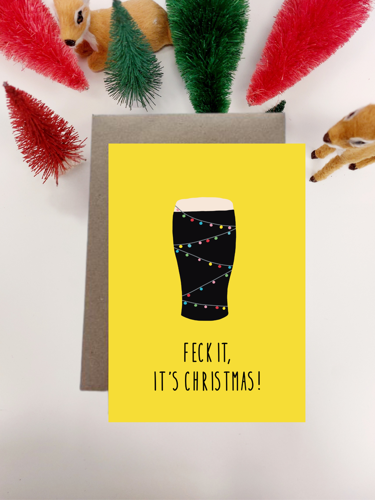 Irish Made Card with a Christmas-themed design featuring a pint glass of Guinness with lights and text 'Feck it, it's Christmas!' on a yellow background.